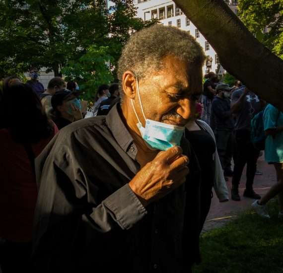 man in black jacket holding white plastic bag